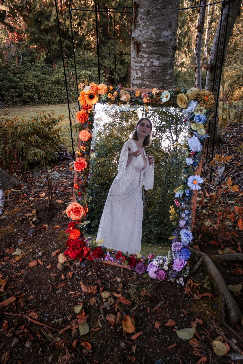 A mirror decorated with colorful flowers frames a dreamy portrait in a magical forest scene.