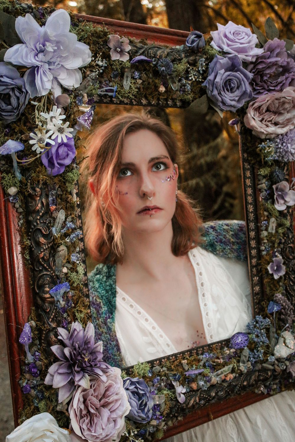 A dreamy portrait series featuring an ornate frame adorned with purple and blue flowers in a forest setting.