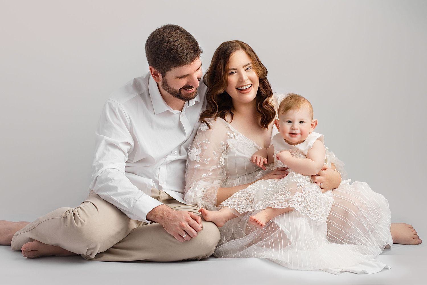 Family in coordinating blue and white outfits pose together against dark backdrop in studio portrait session. Northside, family portraits, i