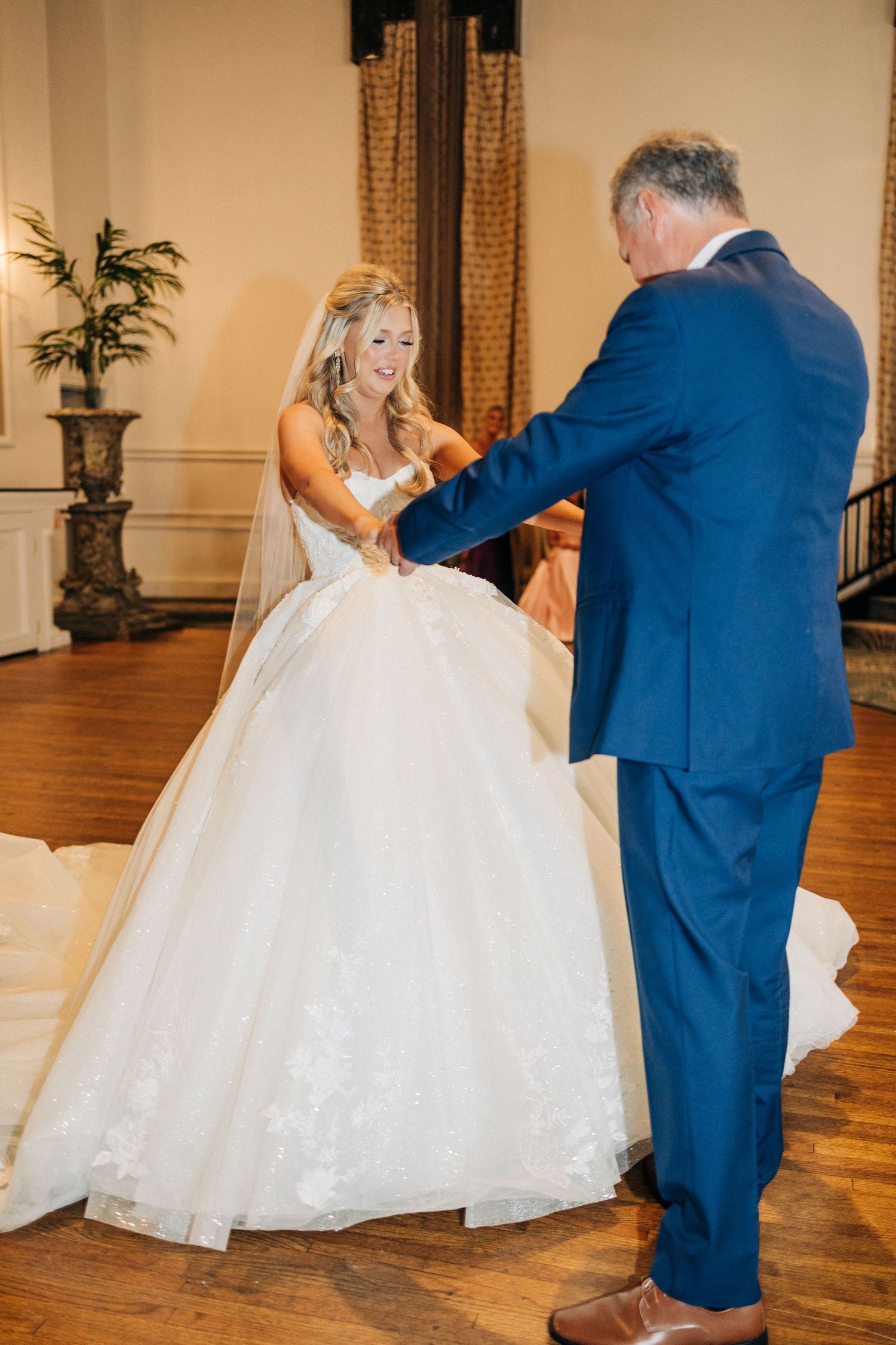 A tender moment during a first dance in an elegant venue with hardwood floors and a rich interior setting.