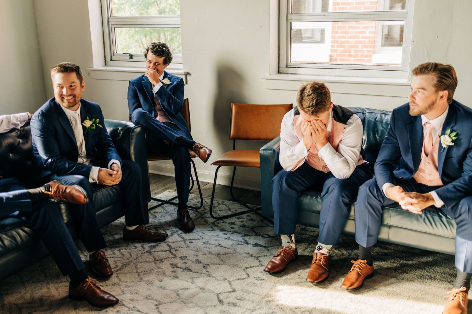 People sitting on couches and chairs in a relaxed indoor setting with natural light coming through windows.