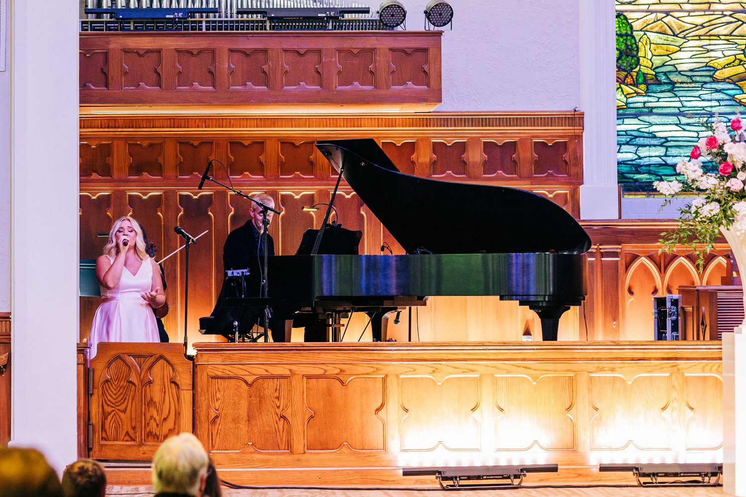 Musicians perform on a colorful stage decorated with ornate architectural details at a concert venue.