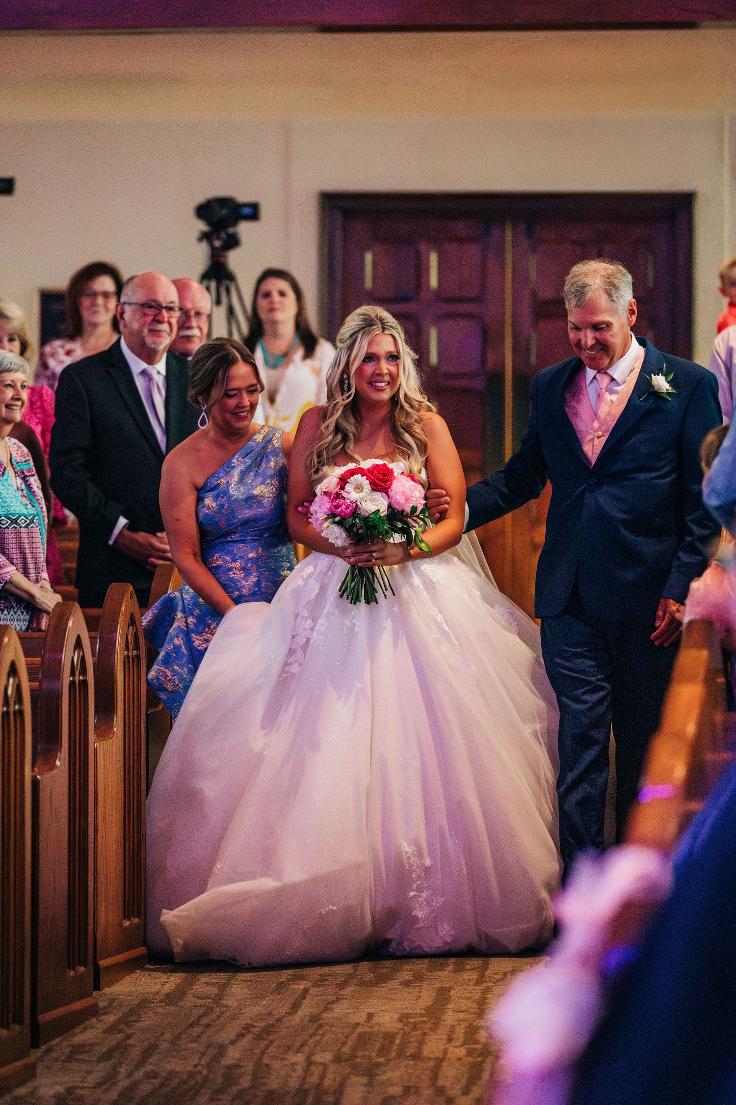 Traditional church wedding processional featuring a flowing white princess ballgown dress walking down the aisle.