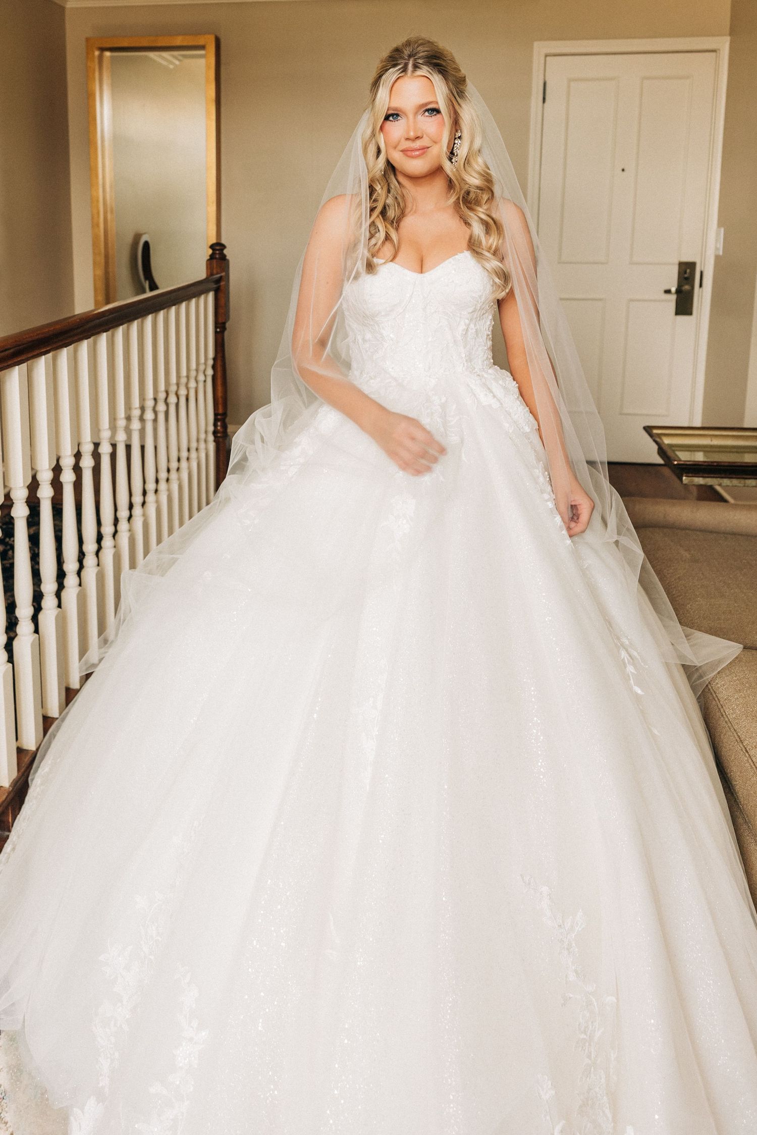 Beautiful bride poses in a stunning white ball gown wedding dress with delicate lace details and a full tulle skirt.