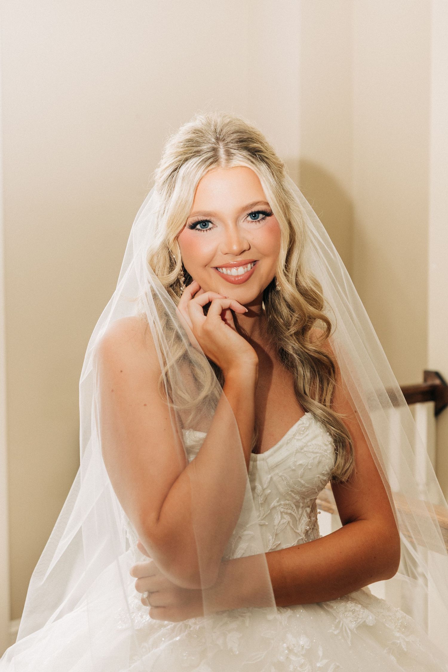 A bride in a white wedding dress and veil poses elegantly on the floor in a series of artistic bridal portraits.