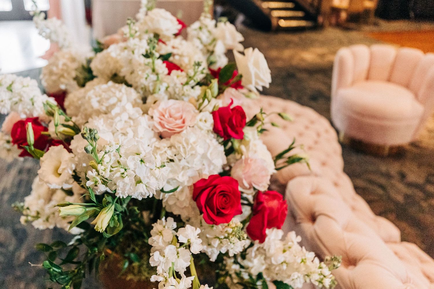 A luxurious floral arrangement featuring white hydrangeas, red roses, and pink blooms for a wedding reception.