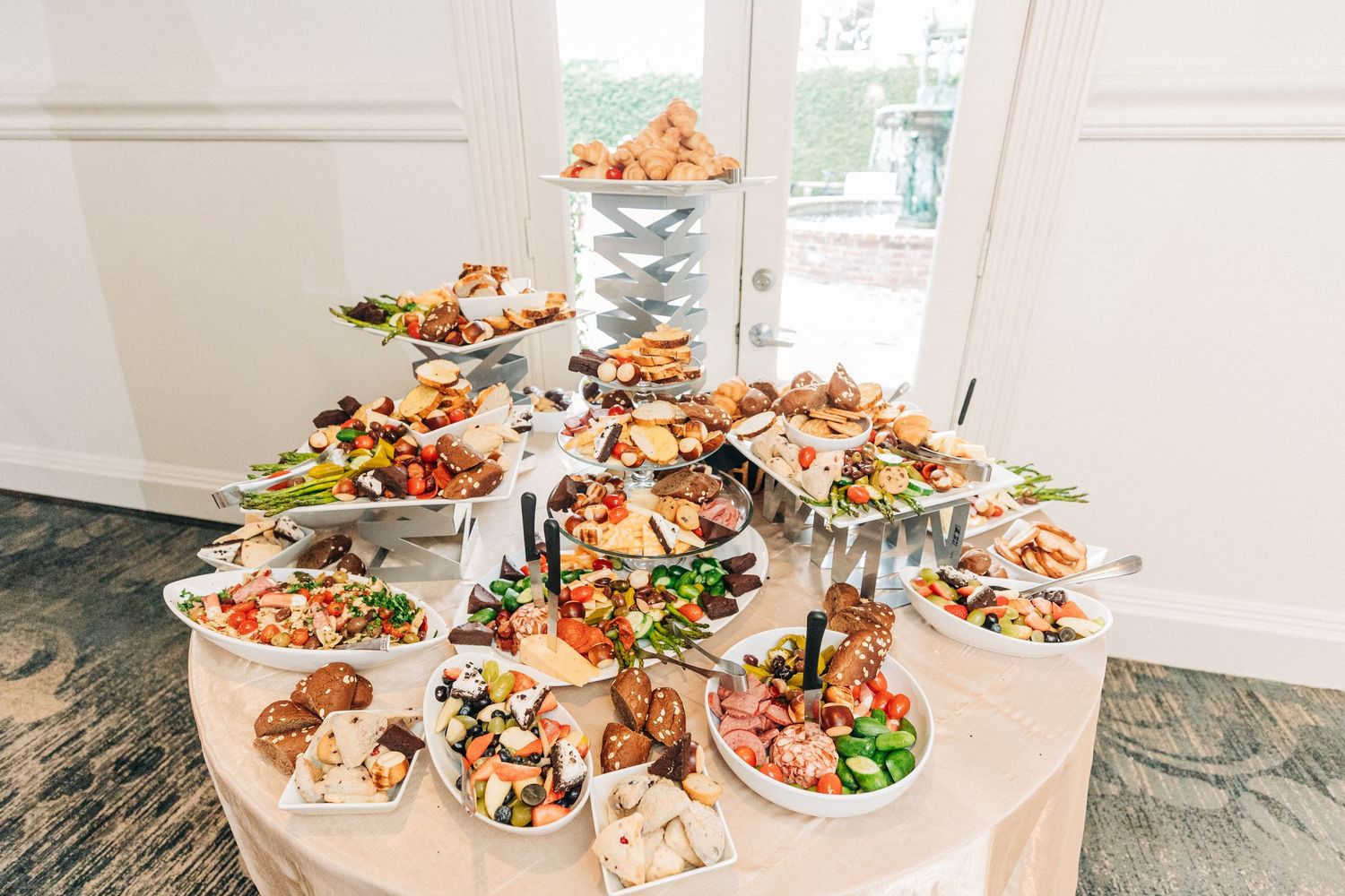 A beautifully arranged catering display of seafood and appetizers on white tables in a bright room.