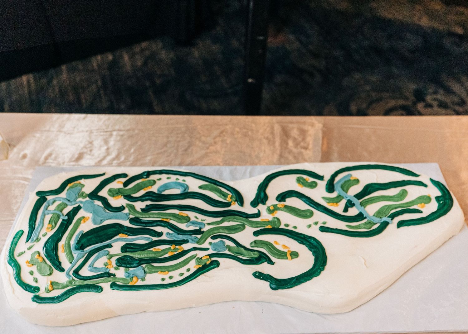 Green and white swirled pattern painted on a beige surface resembles a flowing abstract design.