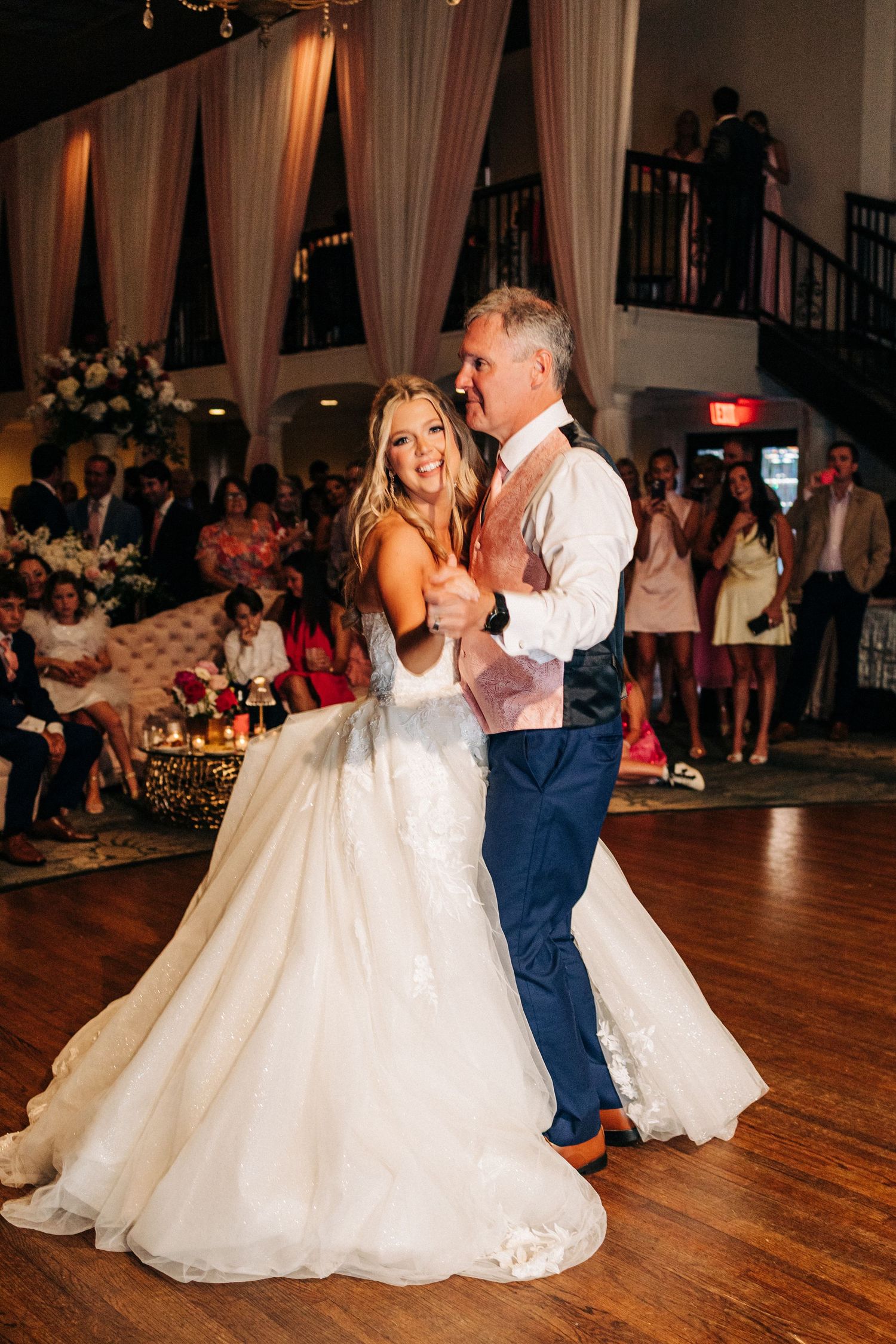 A couple shares an intimate dance moment on a hardwood floor during their wedding reception.