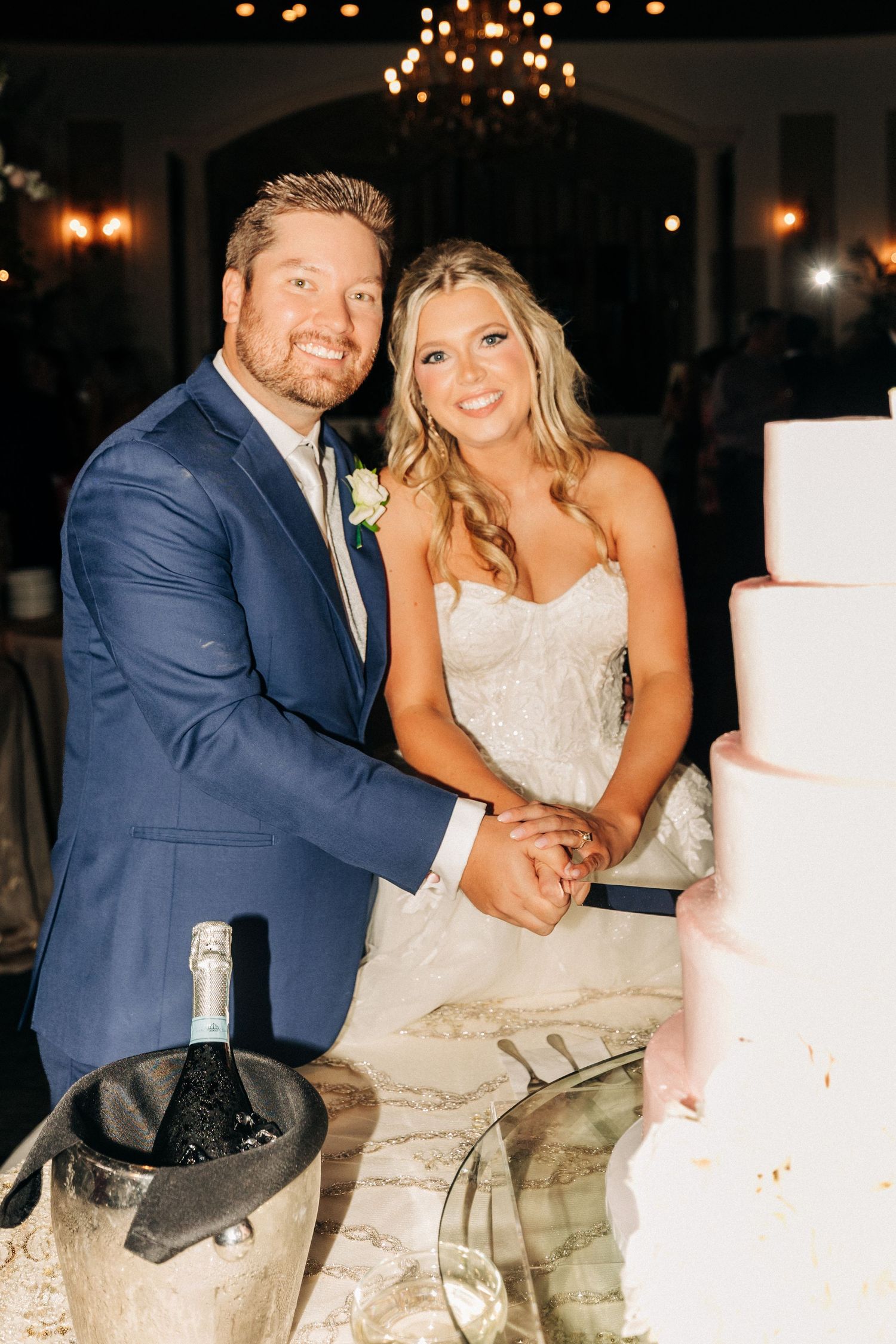 Series of shots showing bride and groom playfully cutting and sharing their white wedding cake under twinkling lights.