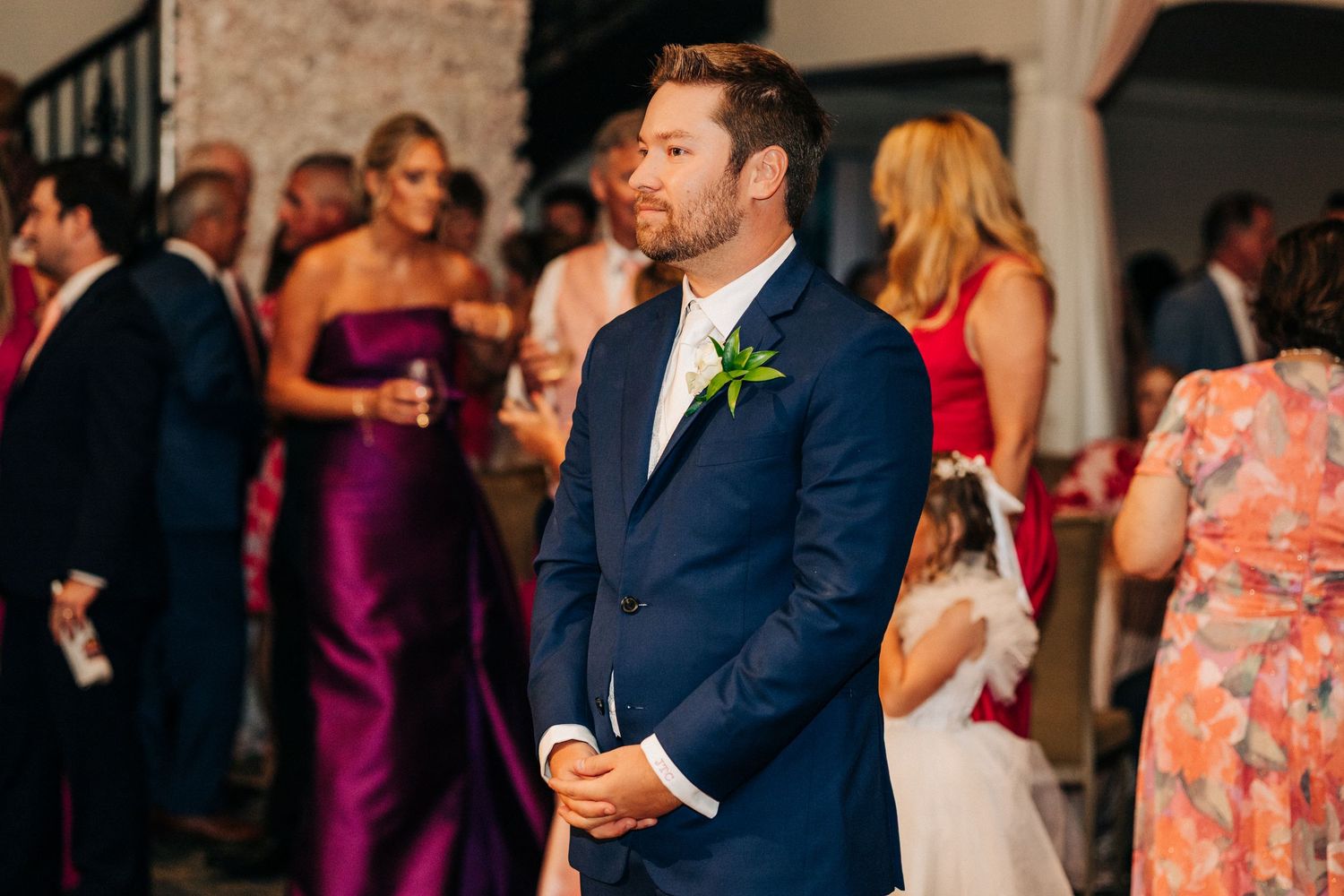 Wedding reception guests dancing and celebrating together at an elegant indoor venue with soft lighting.