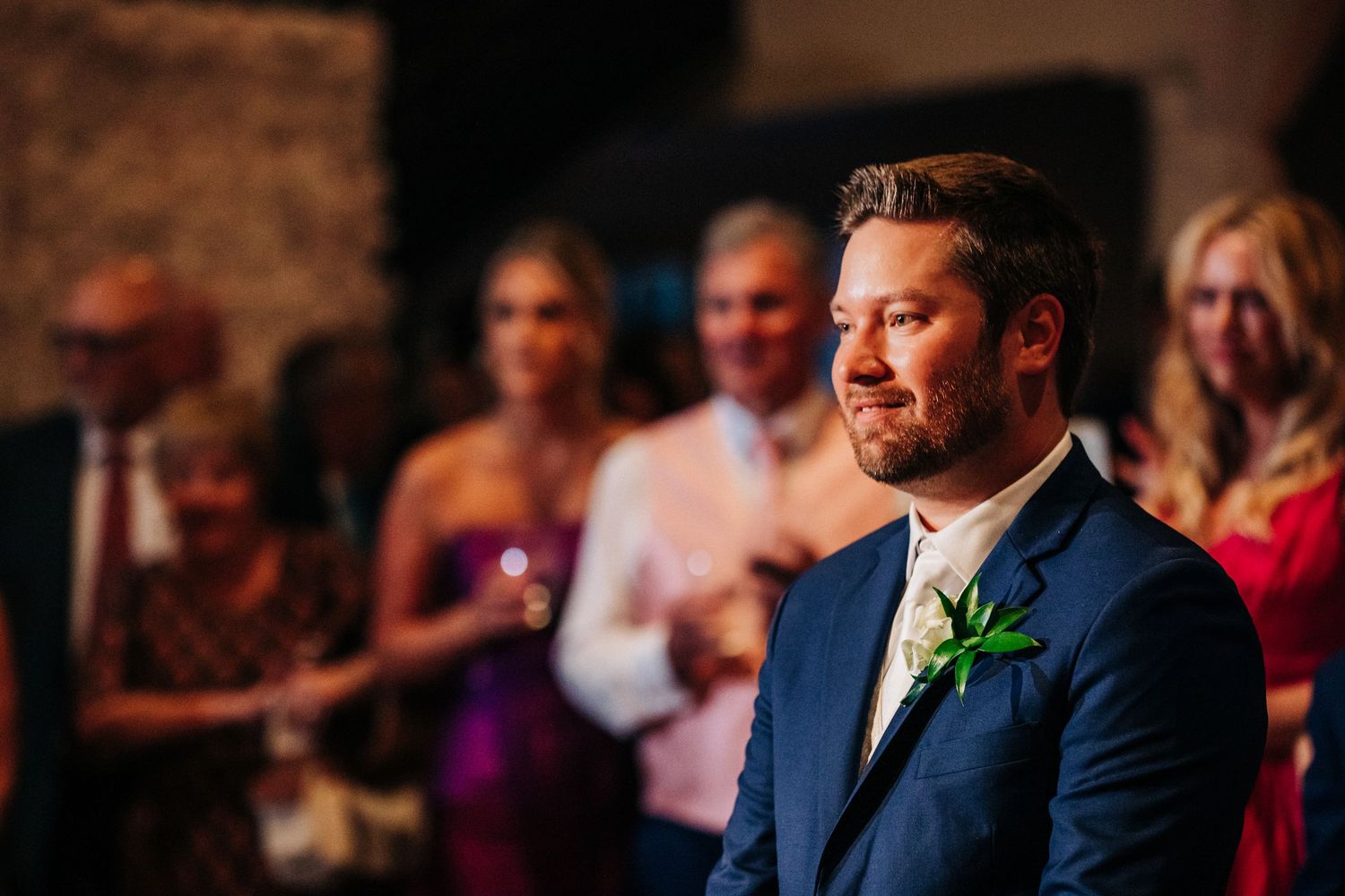 An emotional moment captured at a wedding reception with guests smiling in the background.