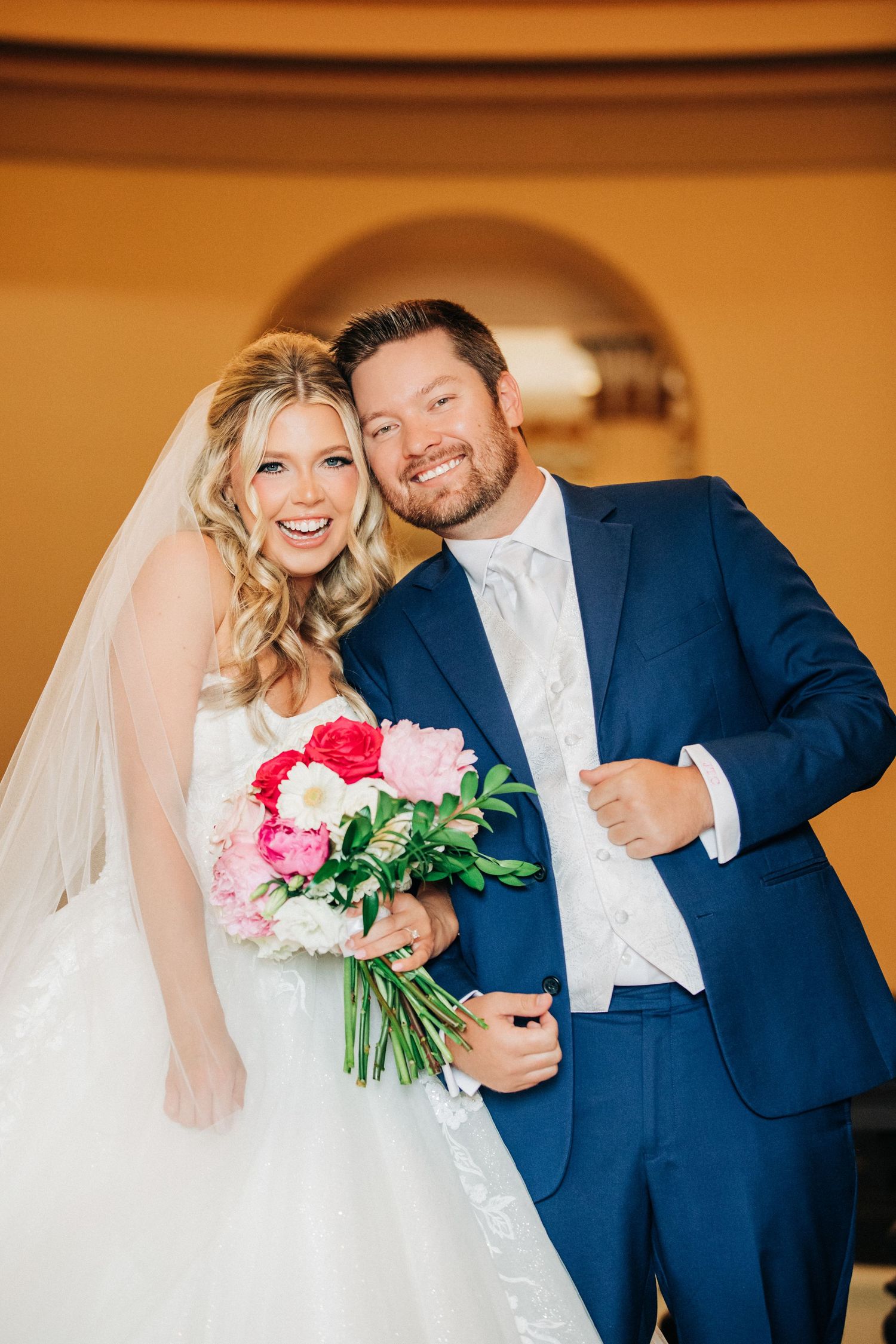 Joyful wedding couple shares intimate moments in sequence wearing classic navy and white with pink flowers.