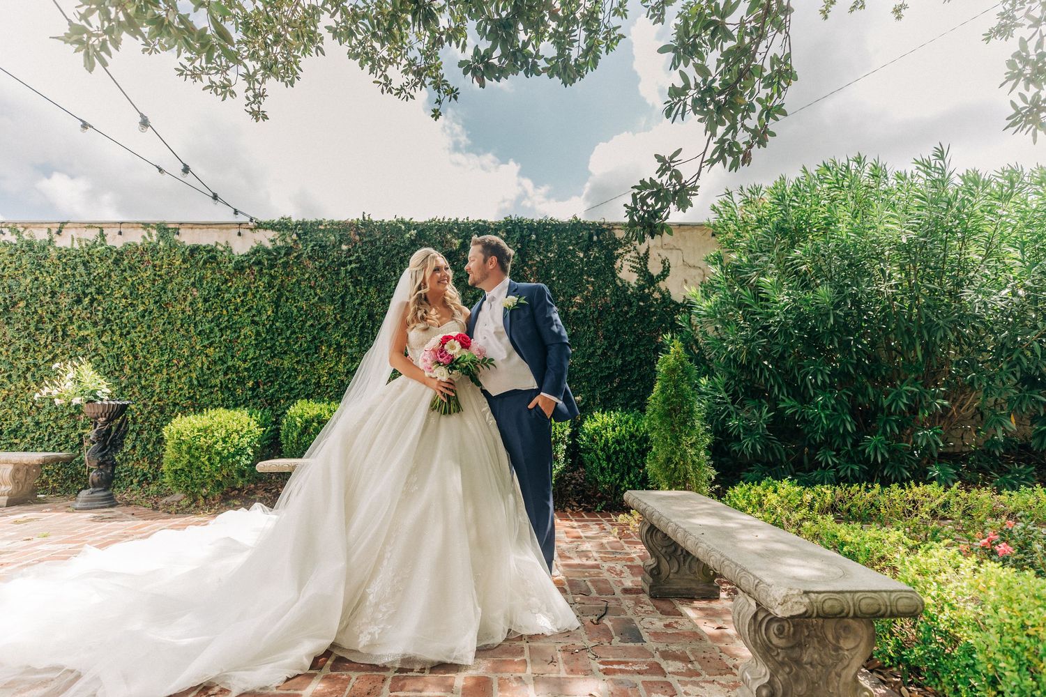 Romantic panoramic view of wedding couple in lush garden setting with sweeping landscape composition.