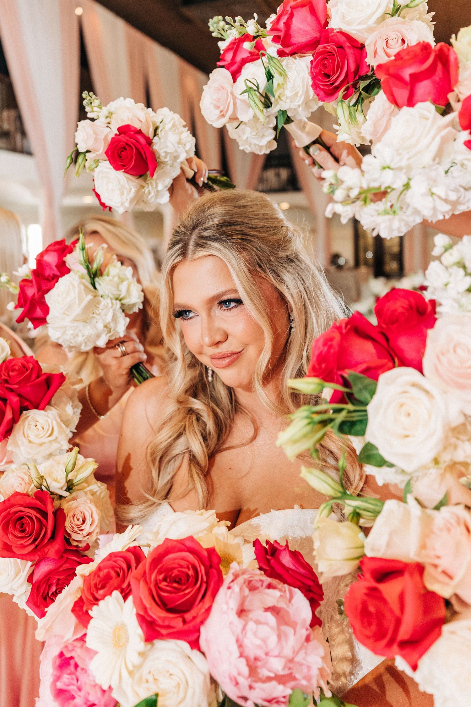 Elegant floral arrangement of pink and coral roses with white peonies and greenery creating a romantic wedding atmosphere.