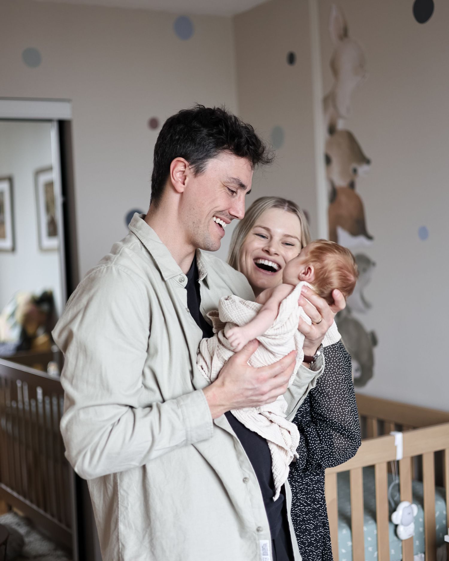Candid moments of a couple holding and laughing together in a nursery room with stuffed animals on the wall.