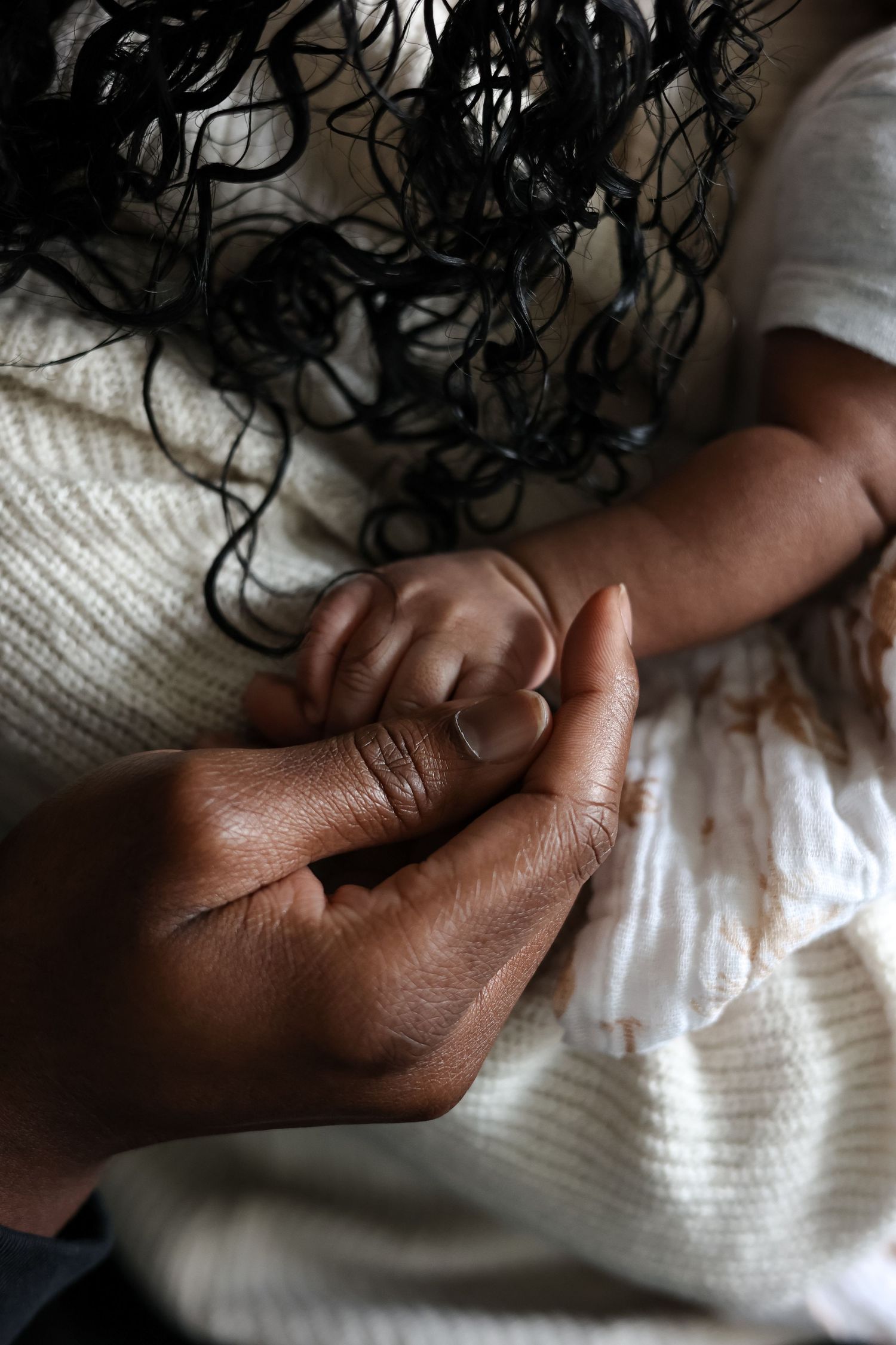 Two hands in close-up shots and various positions holding white fabric or sheets against a dark background.
