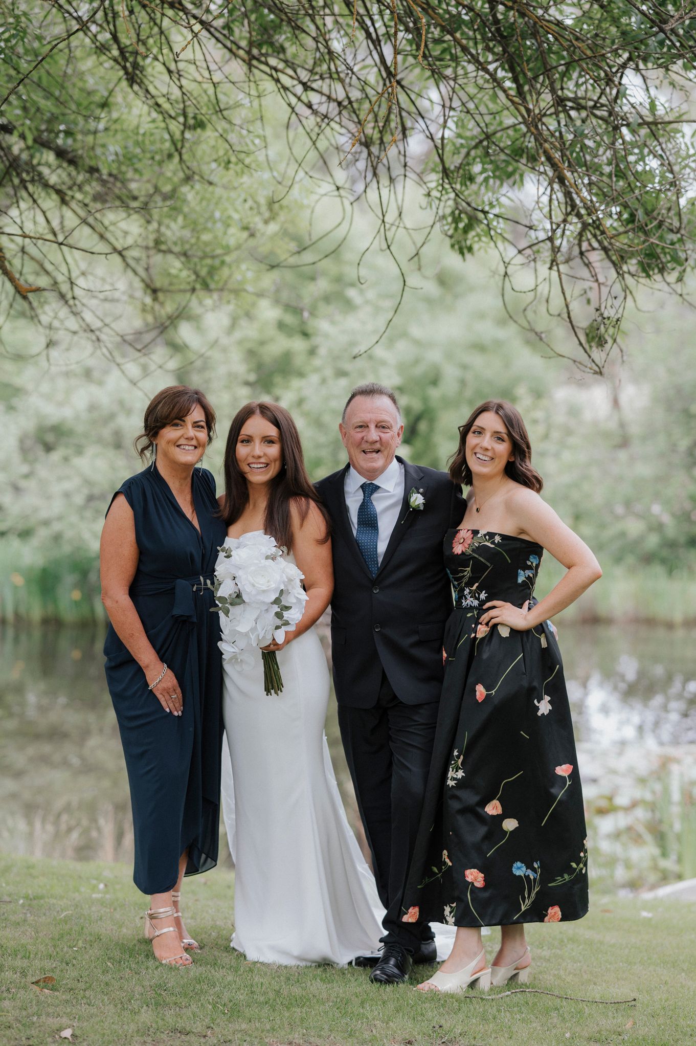 Family photos taken beside a serene lake with trees in the background.