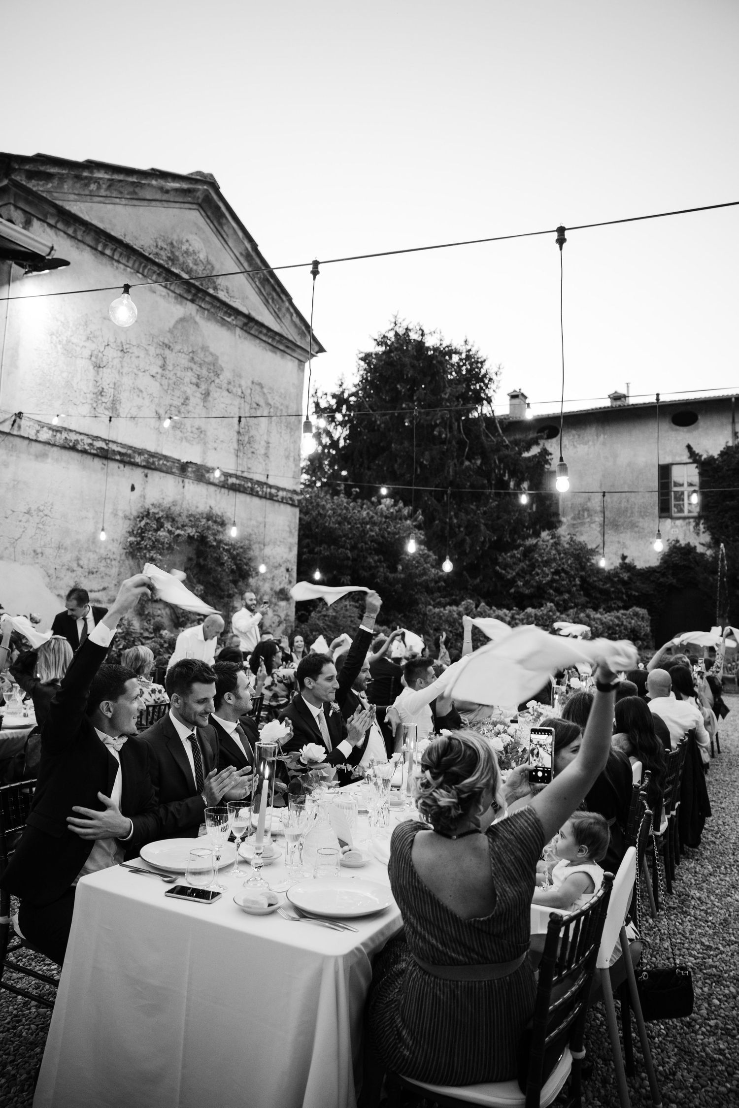 A black and white photo series showing an outdoor wedding dinner reception with guests seated at long tables.