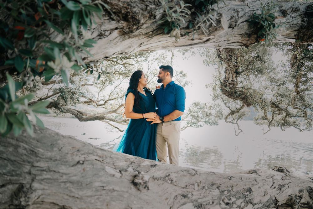 A couple in coordinating blue outfits share a romantic moment against a white limestone cave backdrop during their photoshoot.