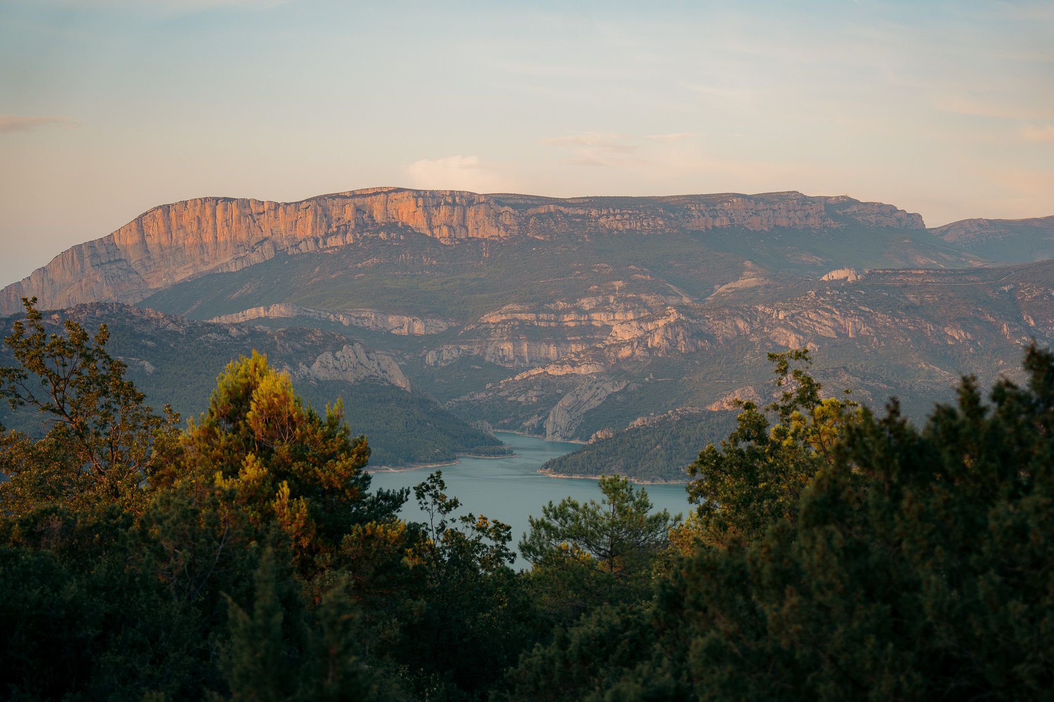 Dramatic red cliffs and mountain ranges stretching across the horizon at dusk.