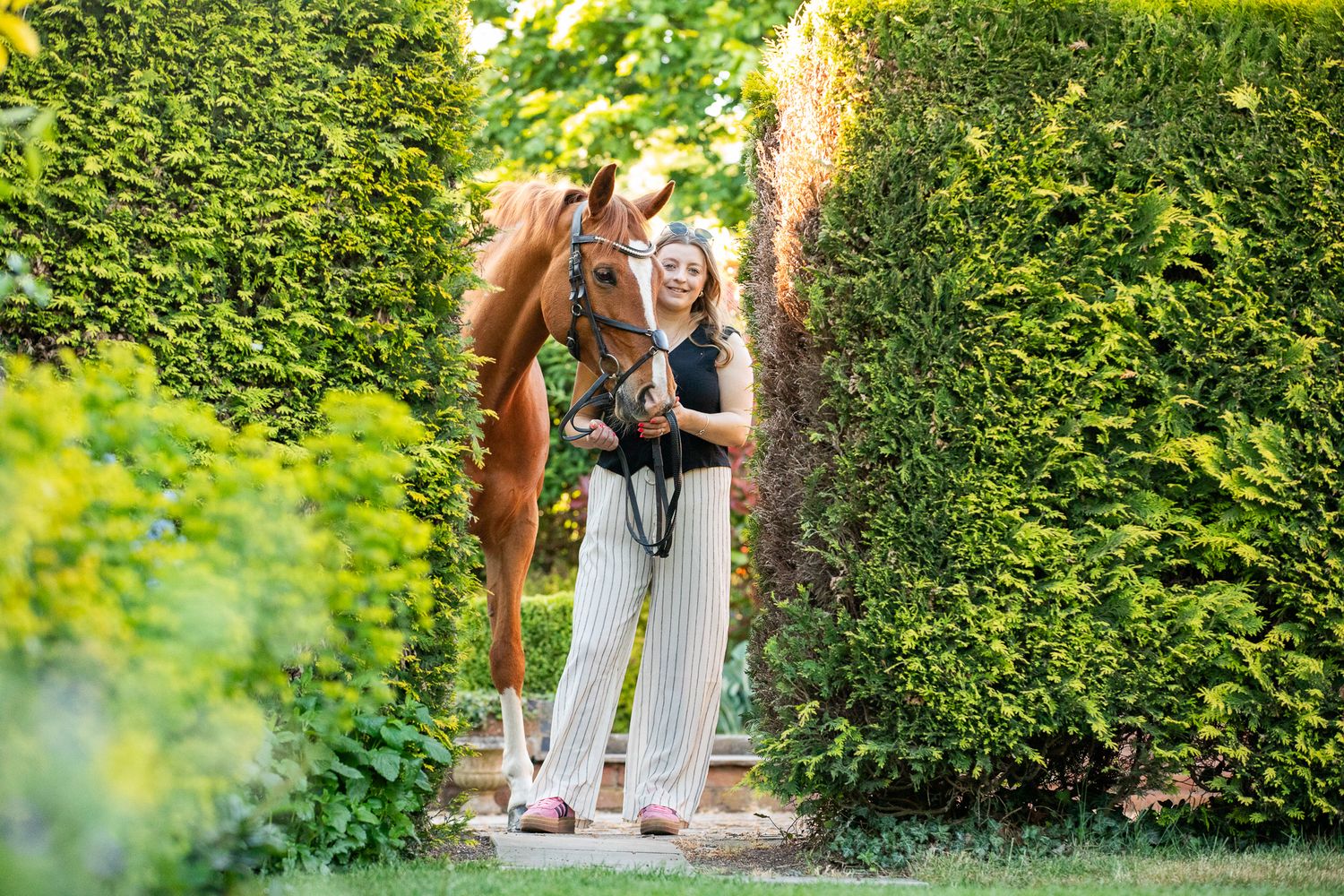 A beautiful black and white paint horse stands with a person on a sunny autumn day outdoors.
