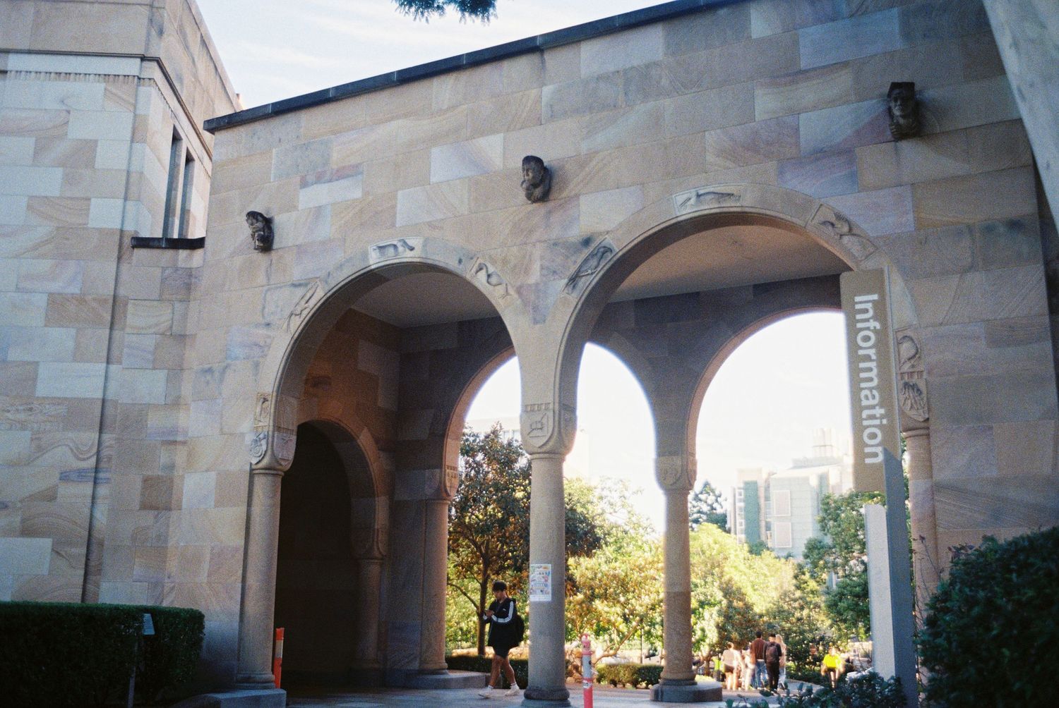 Stone archway corridor with curved arches and columns in a Mediterranean architectural style extends along a building exterior.