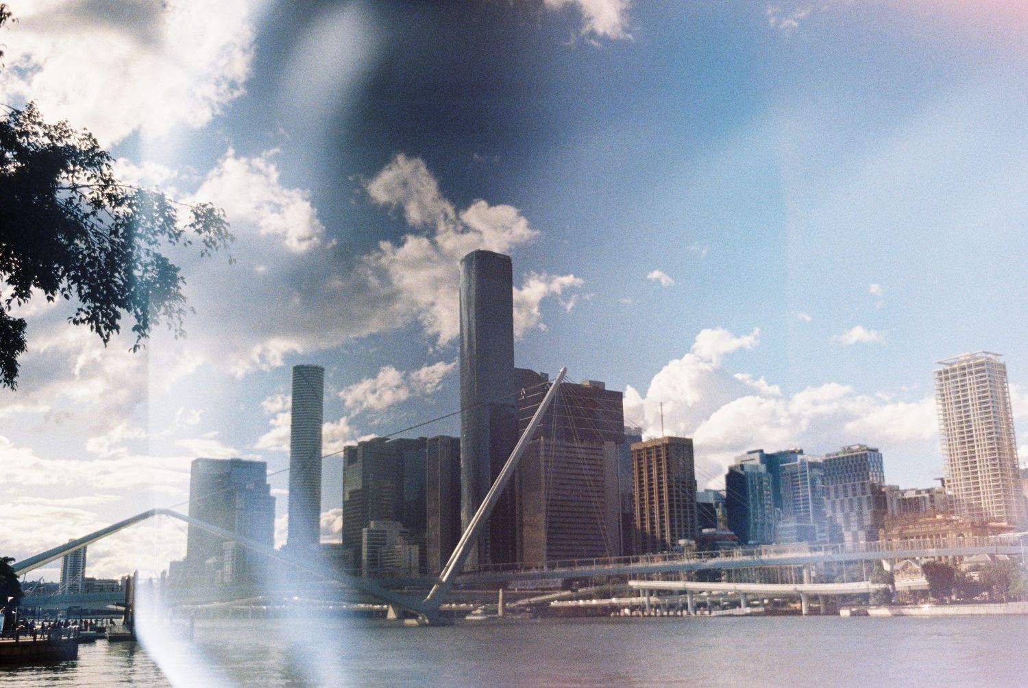 Urban skyline view of tall buildings and skyscrapers along a waterfront with dramatic cloudy sky.