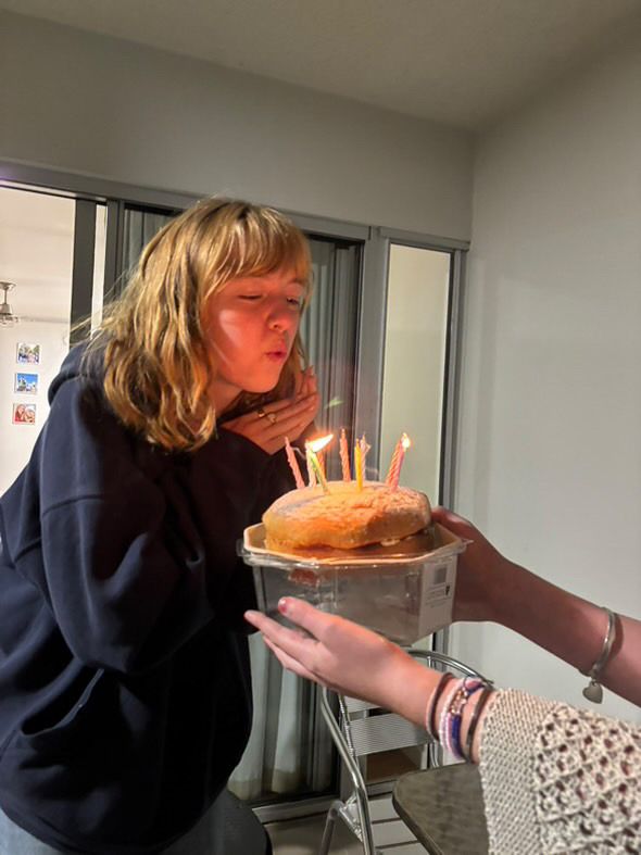 A birthday celebration moment with lit candles on a cake in a dimly lit room.