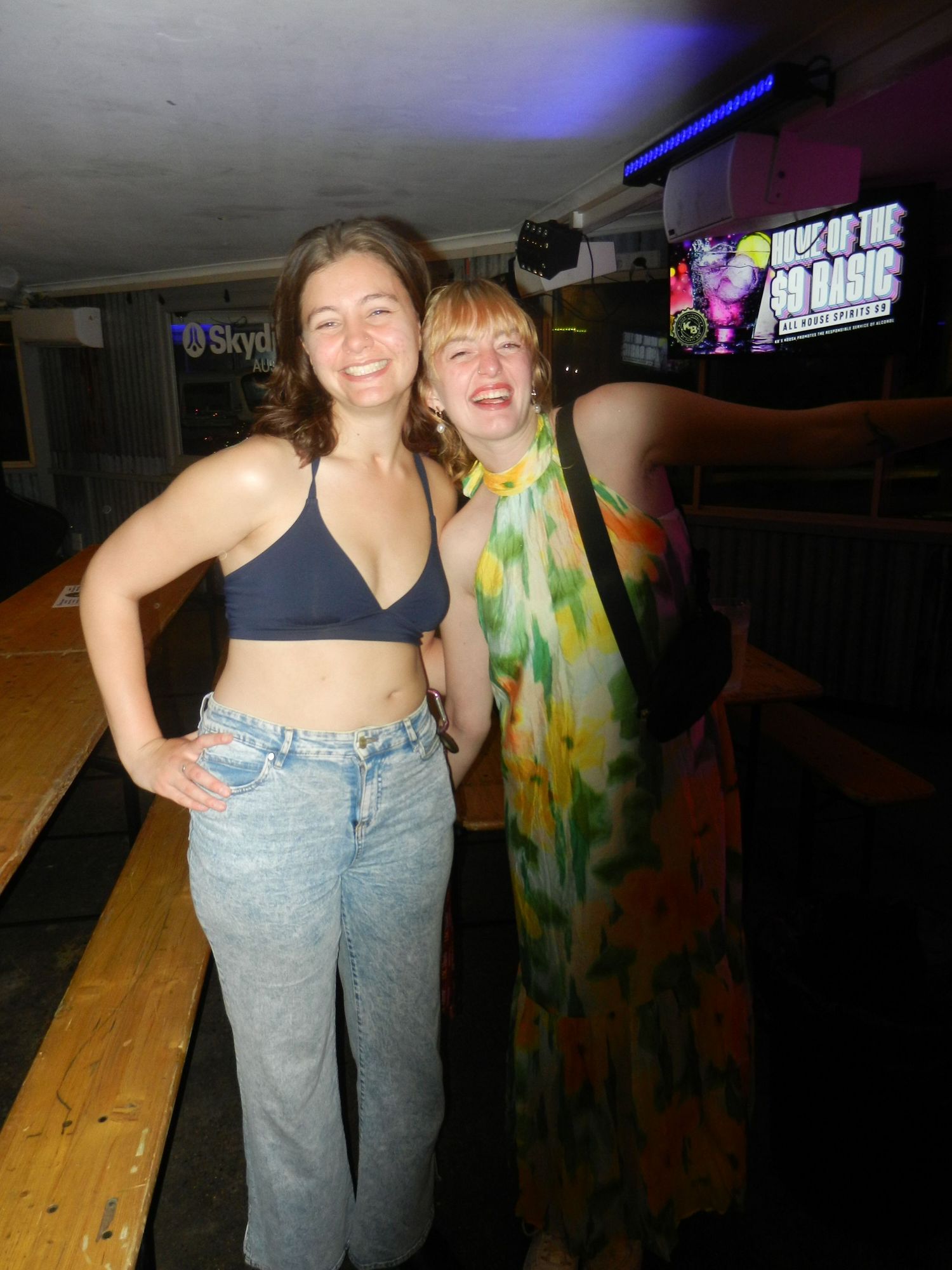Two people enjoying a night out at a club with colorful lighting and casual attire.