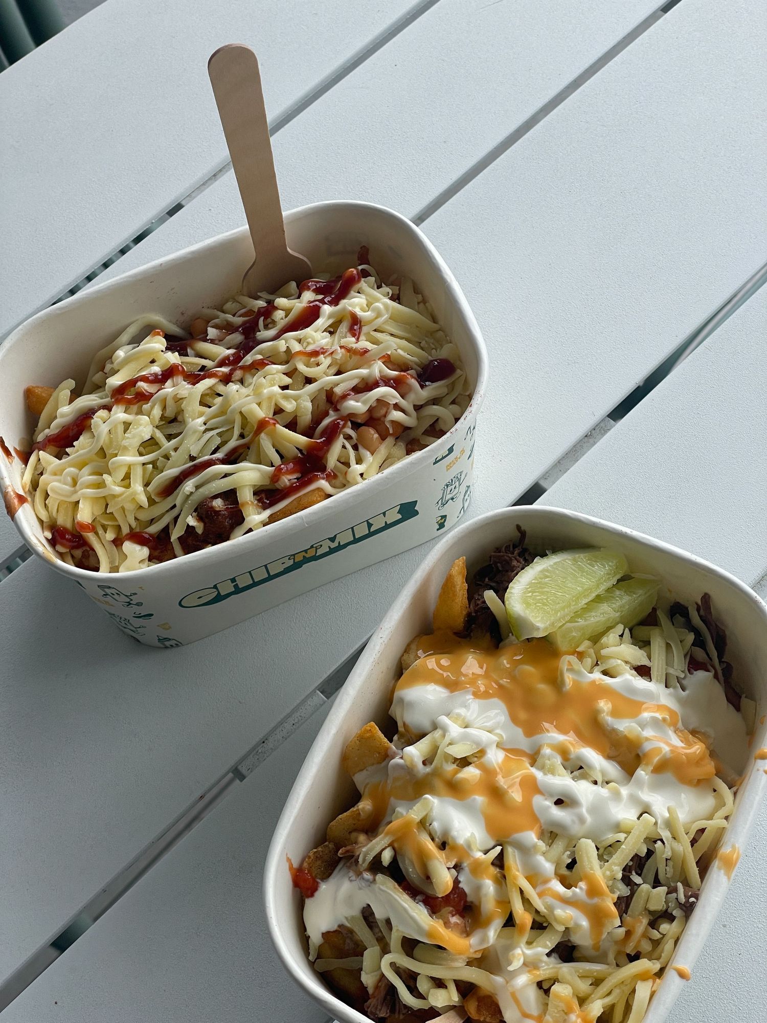 White takeout container filled with fresh taco bowl topped with shredded lettuce and creamy sauce.