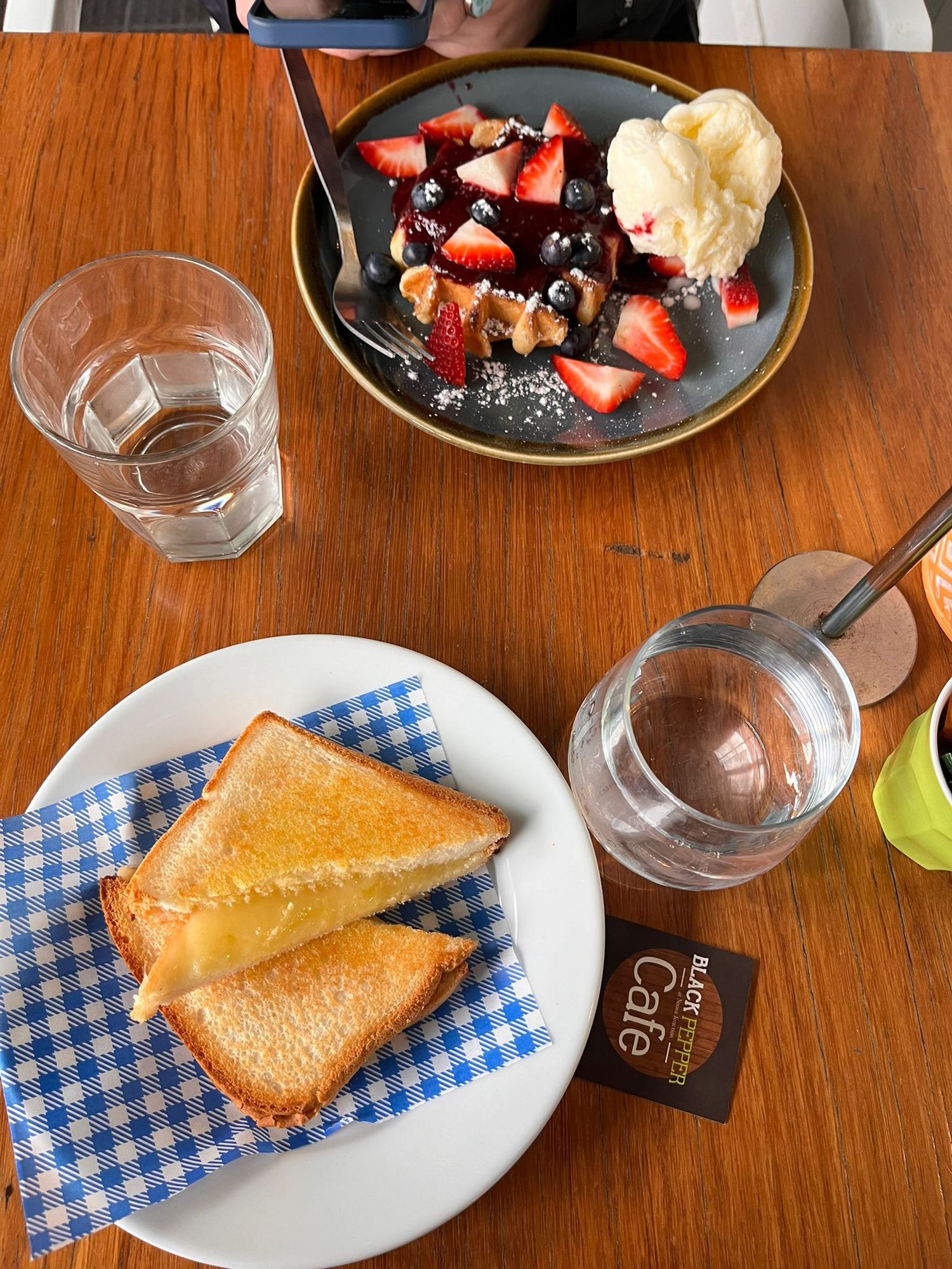 Breakfast spread with toast, strawberries, and glasses of water on a wooden table.