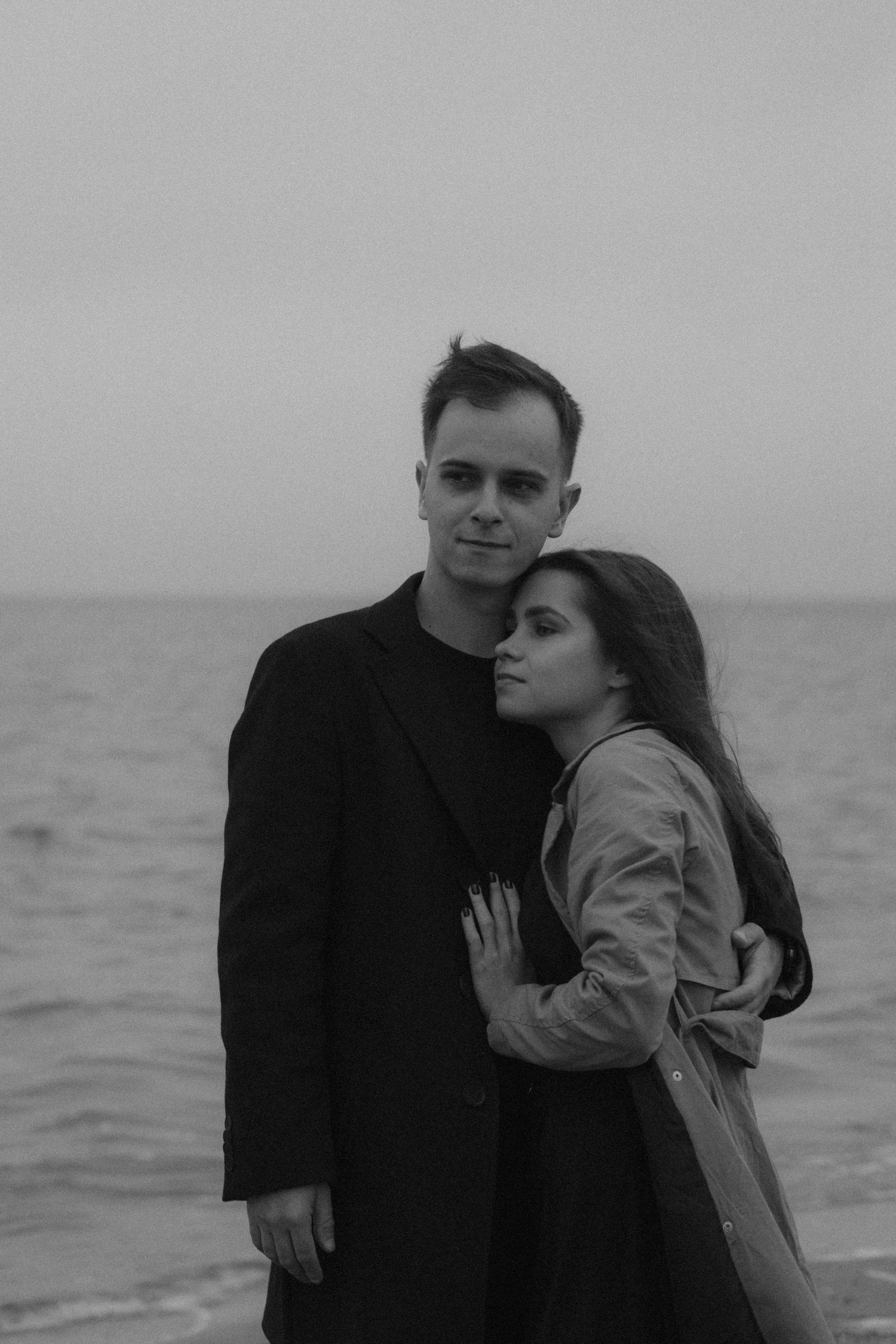 A four-panel black and white sequence shows a couple embracing by the sea.