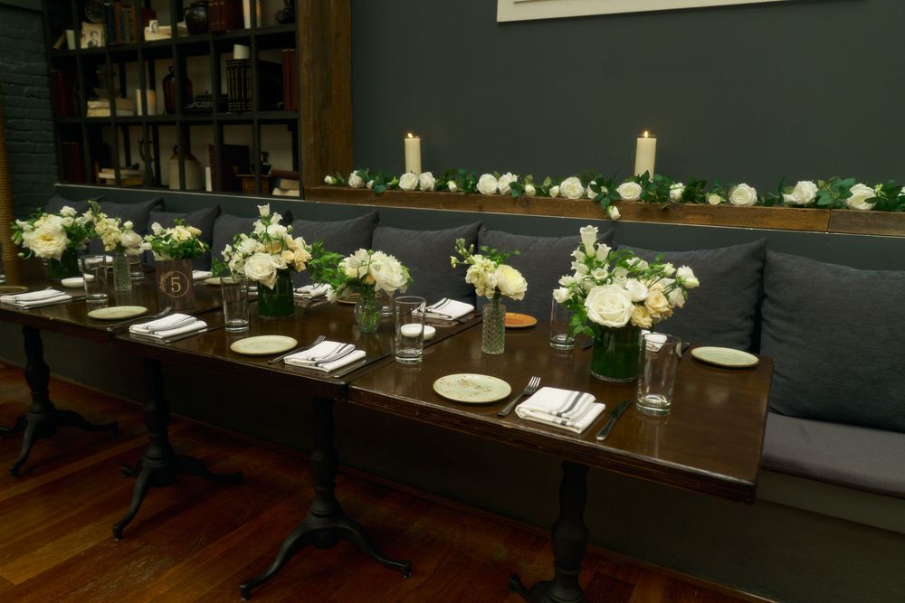 Elegant table settings with white floral centerpieces in a modern dark-walled dining space at the Milling Room