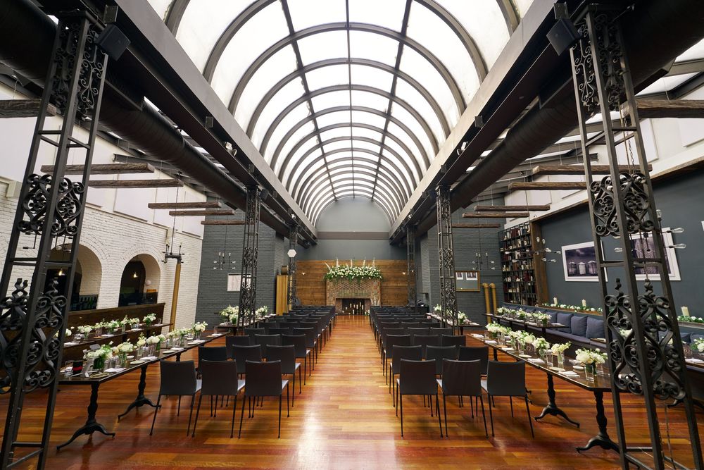 An architectural view of a reception venue with arched skylights and hardwood floors at the Milling Room