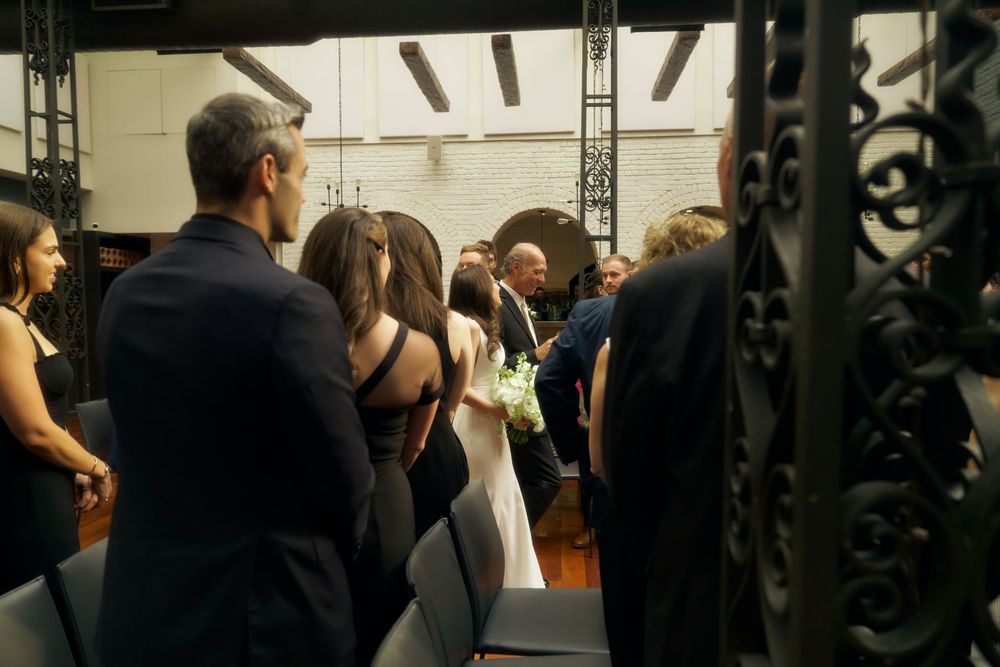 A group of people gathered at an indoor event space with ornate black ironwork visible in the foreground at the Milling Room