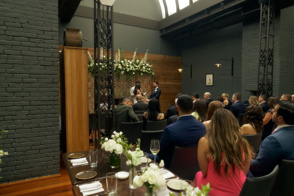 Evening wedding celebration in an intimate venue with black brick walls, elegant floral arrangements and table settings at the Milling Room