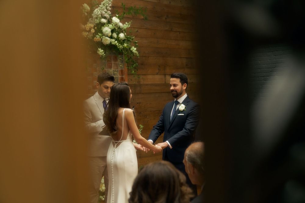 Wedding couple holds hands during emotional ceremony in elegant wooden paneled venue with natural light at the Milling Room