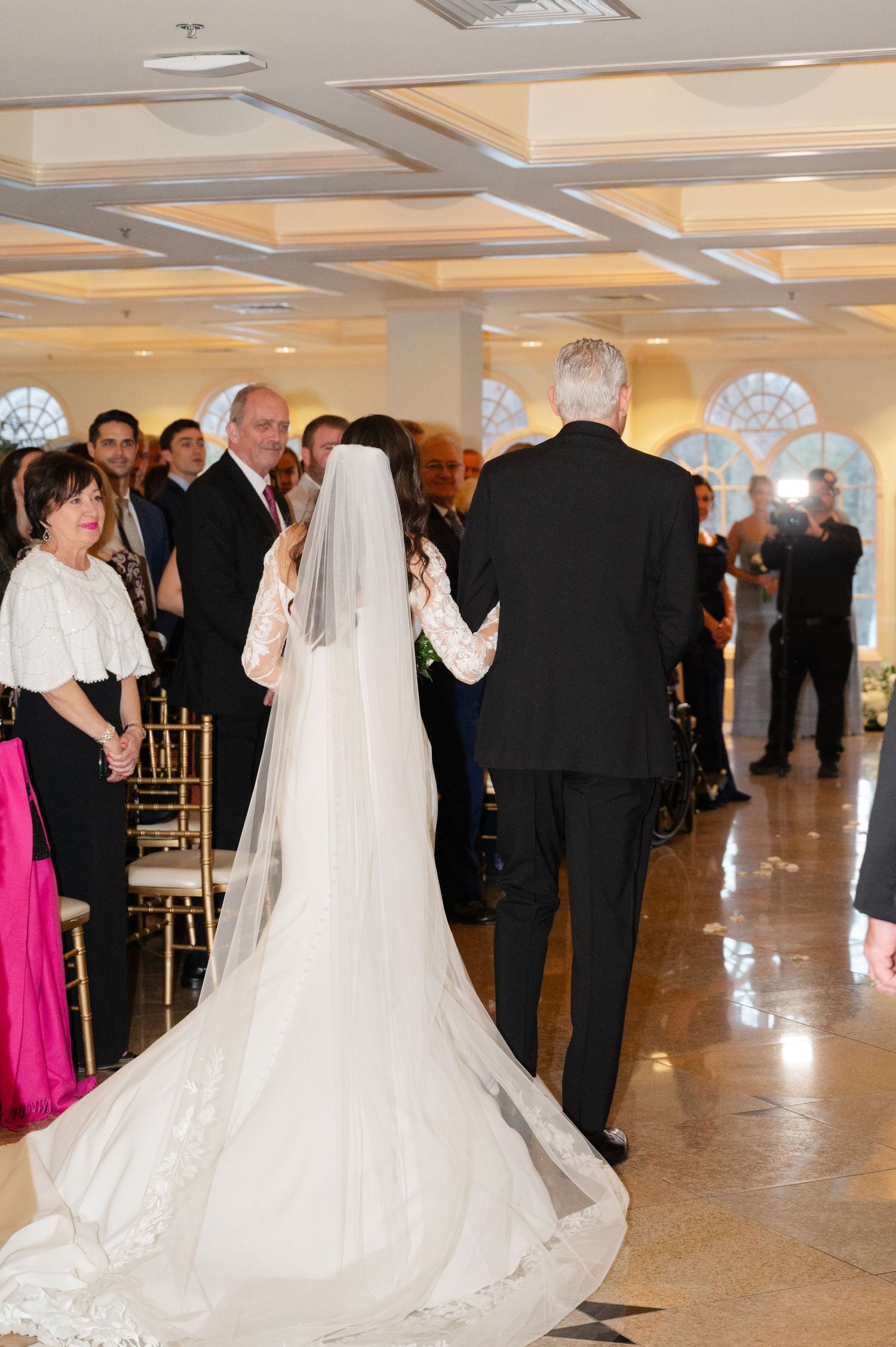 A winter wedding ceremony at the Waterview in CT with a bride wearing a long flowing veil and white gown with a dramatic train.
