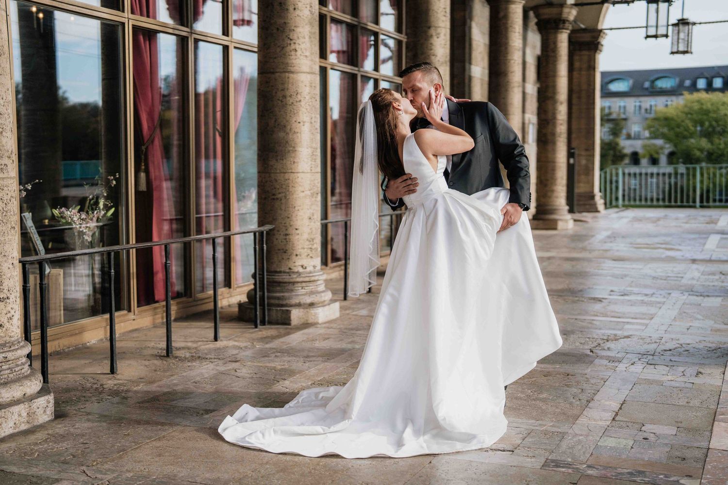 Elegant archway with classic stone columns frames wedding scene.