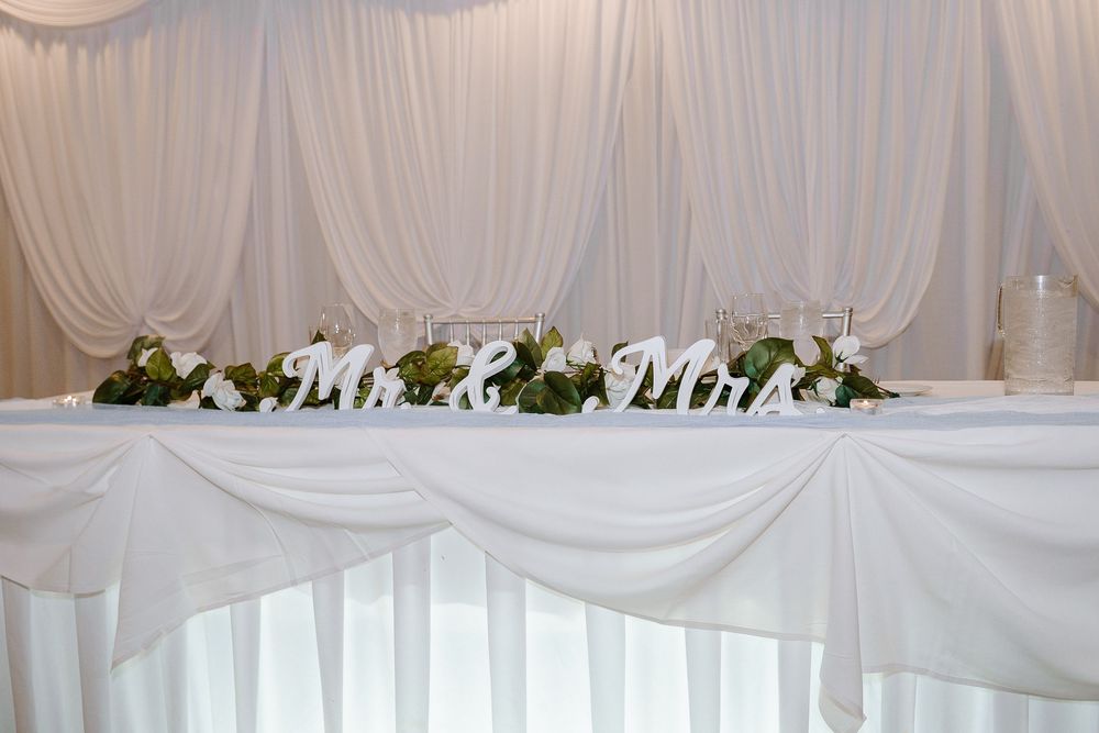 Elegant white wedding stage decor with romantic draping, floral accents, and soft lighting for a luxurious ceremony backdrop.