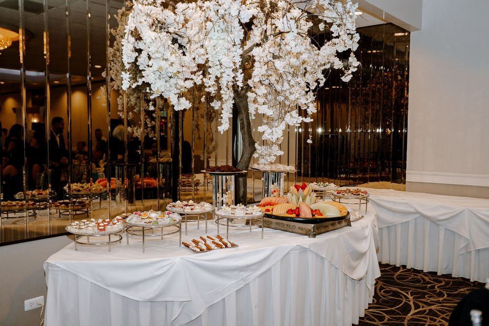 Elegant wedding reception decor featuring crystal chandeliers, white floral arrangements and ornate table settings in a banquet hall.