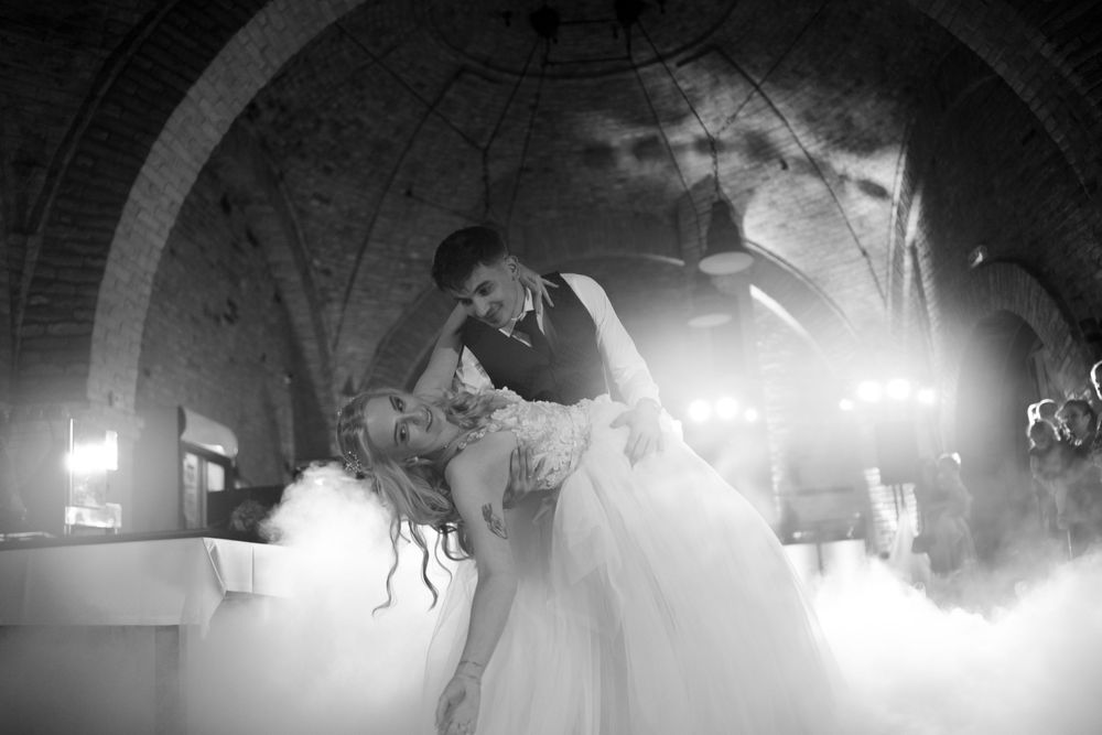 A couple shares a romantic dance dip on a misty dance floor during their wedding celebration at an elegant venue.