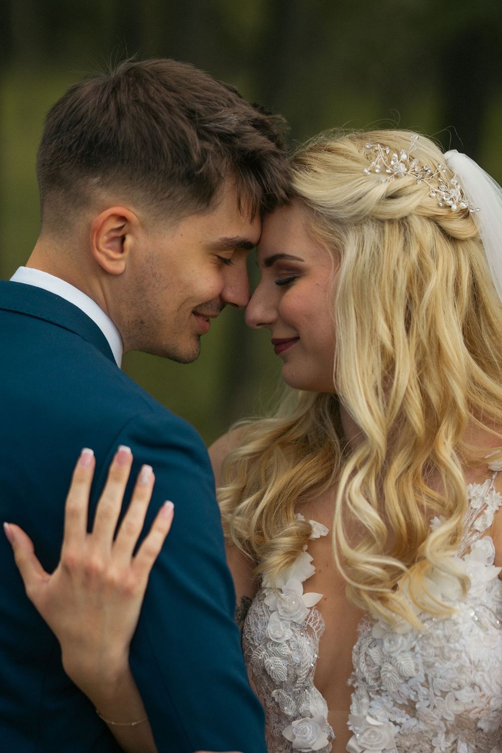 Tender wedding moment showing couple in an intimate romantic pose with the bride in white lace dress and groom in navy suit.