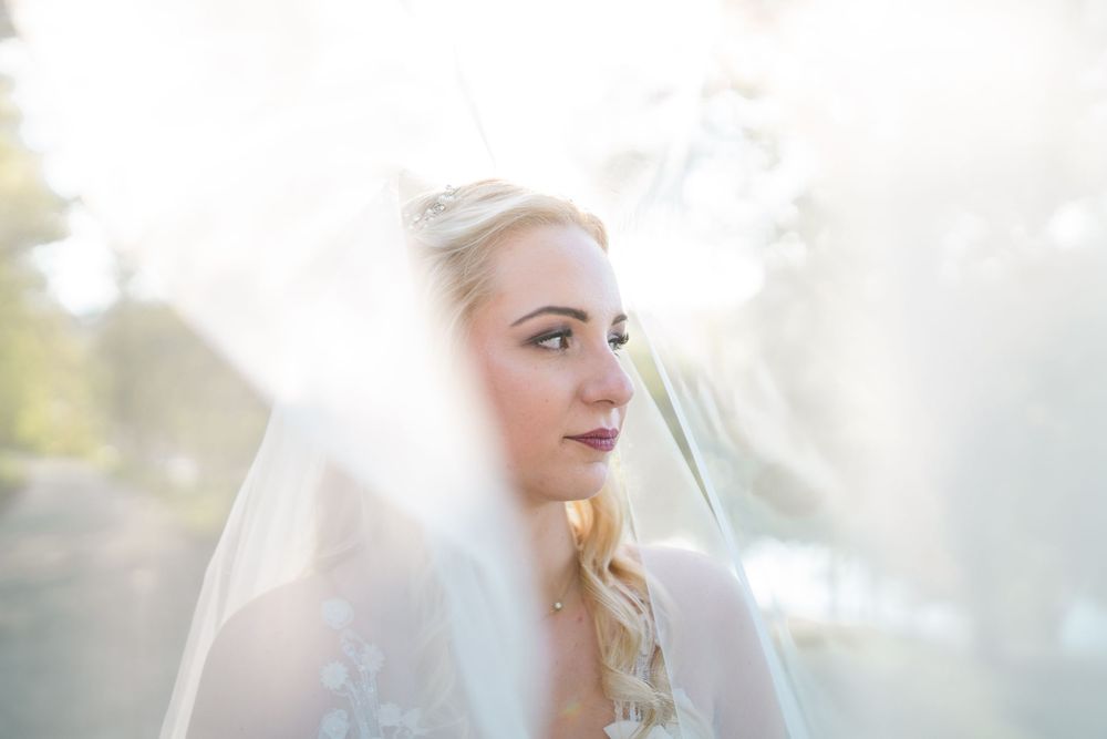 A bride wearing a white veil looks off into the distance with soft light creating an ethereal glow.