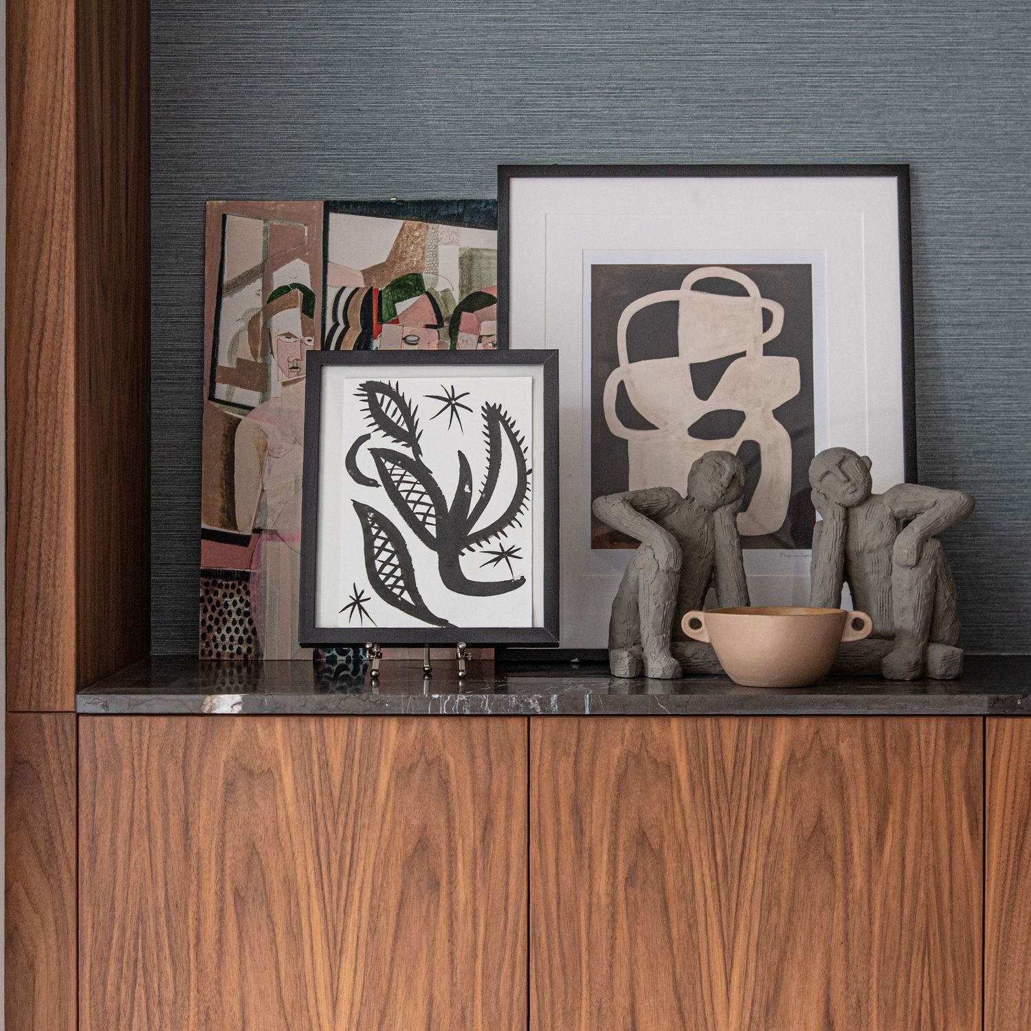 Modern walnut cabinet with abstract black and white artwork displayed against a wooden panel wall. Artwork by Fran Aniorte.