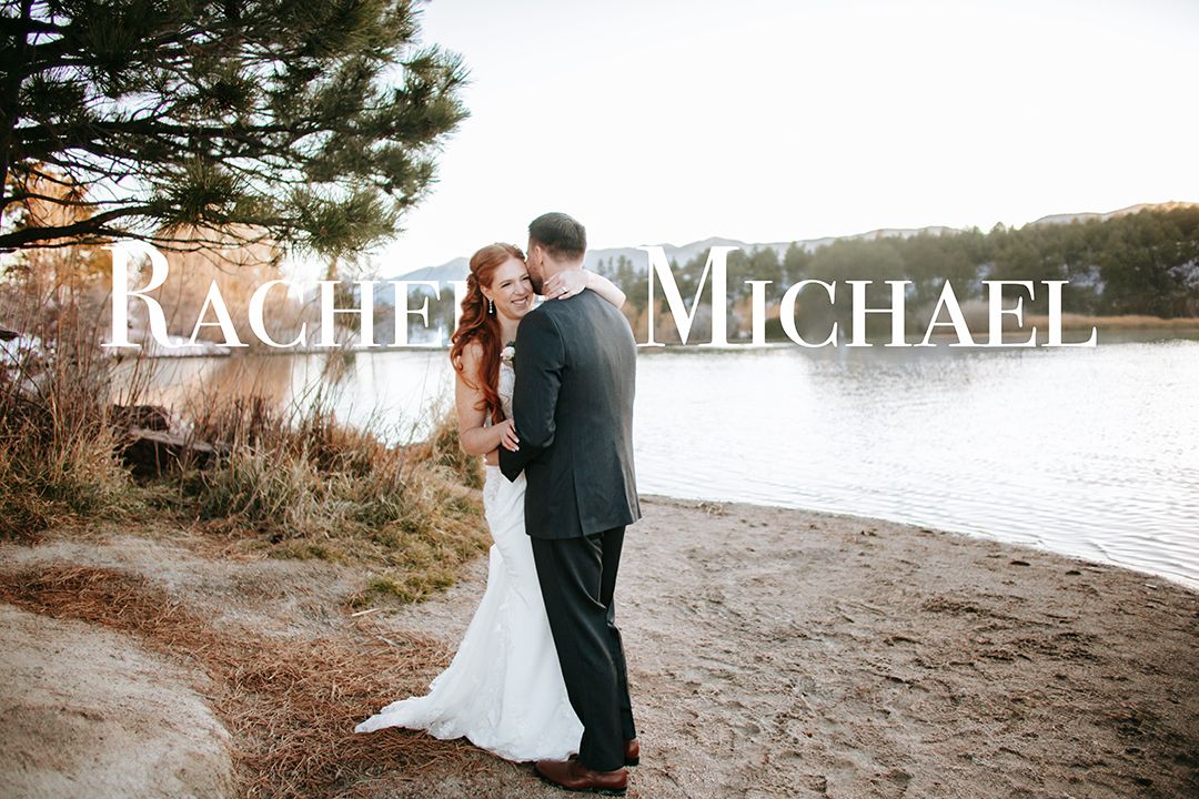 A romantic wedding couple embraces on a rocky beach with pine trees and custom text overlay against a misty backdrop.