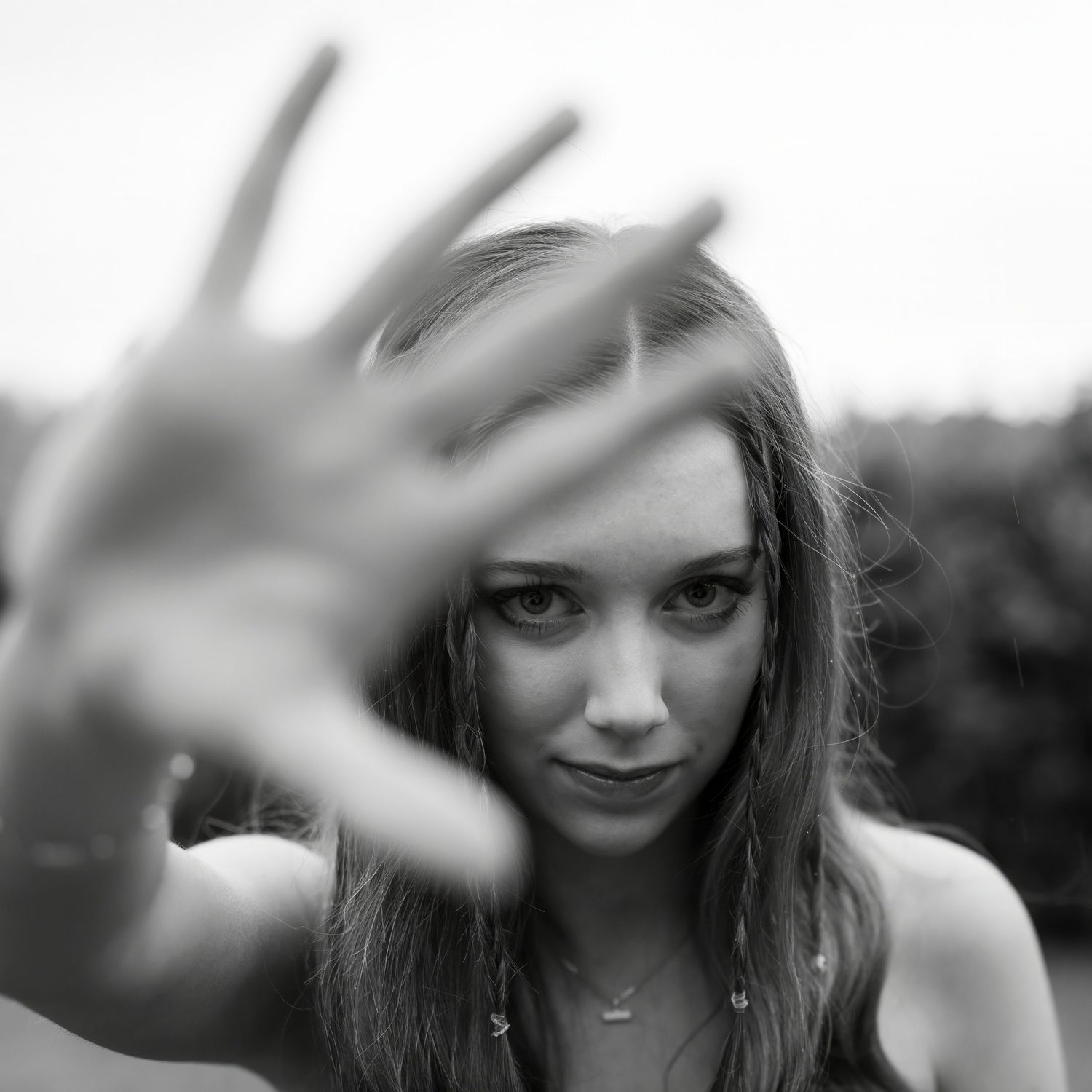 A black and white, eye-level, medium close-up shot of singer Niamh Noade. The person's left hand is extended directly towards the camera.