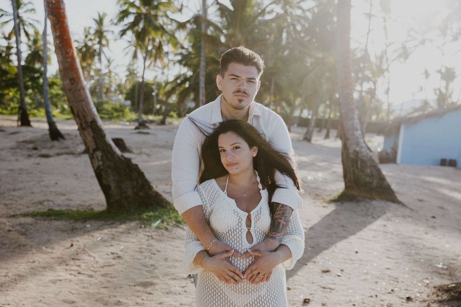 A joyful couple sharing a playful moment on a palm-lined beach.