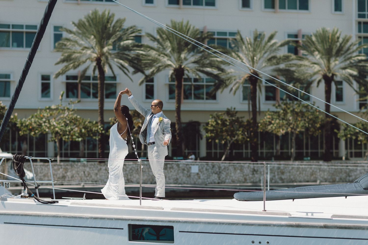 A wedding ceremony taking place outdoors with palm trees and modern architecture in the background.